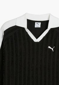 Čierne textúrované tričko s vertikálnymi pruhmi, bielym golierom a malým bielym logom Puma na hrudi. Má výstrih do V.