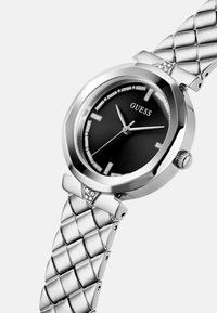 Srebrn iz nerjavečega jekla s črnim č face, osmišljenim ohišjem, diamanti oznakami ur in prešitim zapestnikom.