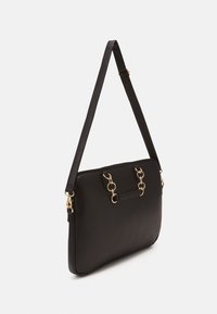 Sort håndtaske i kunstlæder med en glat tekstur, udstyret med guldfarvede beslag, en aftagelig rem og dekorative ringdetaljer.