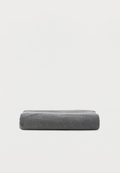 Διπλωμένη πετσέτα σκούρου γκρι χρώματος, τοποθετημένη επίπεδη σε απλό λευκό φόντο.