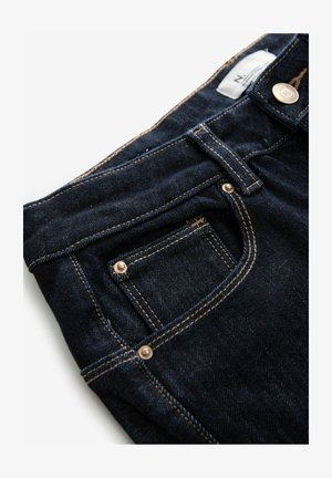 Dunkelblaue Jeans aus Denim mit einer kleinen Fronttasche, kupferfarbener Hardware und kontrastierenden Nähten entlang der Säume. Weiche Textur mit leichtem Glanz.