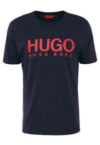 Tmavě modré bavlněné tričko s výrazným červeným nápisem "HUGO" a "HUGO BOSS" v moderním fontu. Klasický kulatý výstřih a krátké rukávy.
