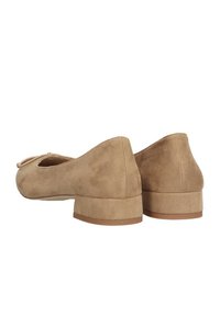 Bailarinas de ante en color beige con un pequeño y amplio tacón, que presentan una punta redondeada y un lazo en la parte delantera. Textura suave con un detalle mínimo.