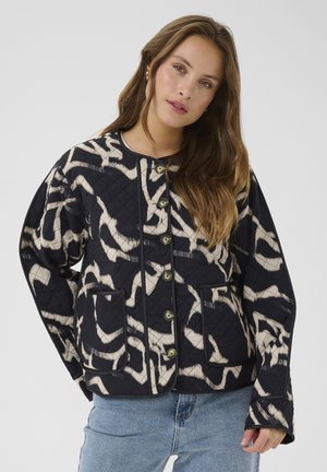 Giacca trapuntata di un blu navy scuro con motivo astratto crema. Presenta un collo rotondo, apertura con bottoni e due tasche applicate. Tessuto liscio.