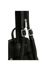 Černý kožený batoh se stříbrným zipem, má dvě popruhy s přezkami a texturovaný povrch.