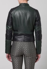 Kožená bunda v tmavě zelené barvě s černými prošívanými akcenty. Má zkrácený střih a hladký povrch, doplněný texturovanými rukávy.