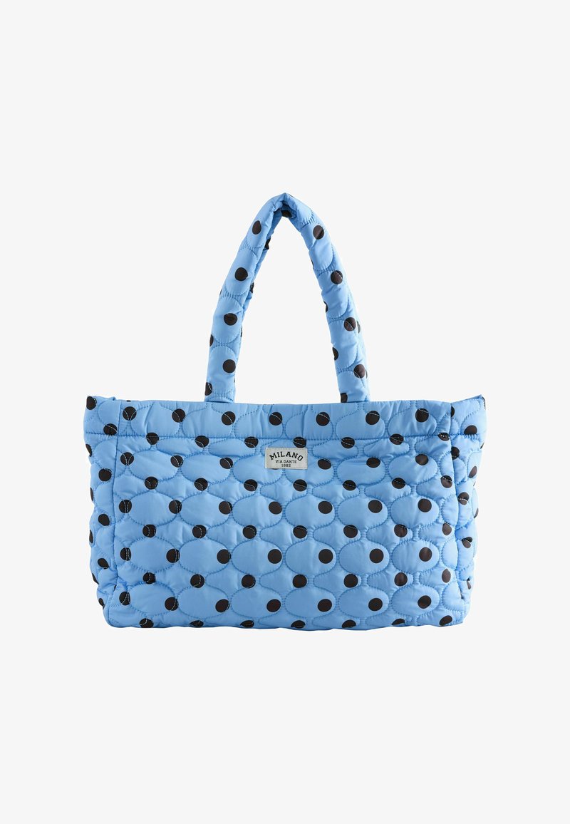 Geantă tote cu matlasare albastru deschis, cu buline negre și mânere duble, având o etichetă mică "Milano Via Dante 1982" pe față.