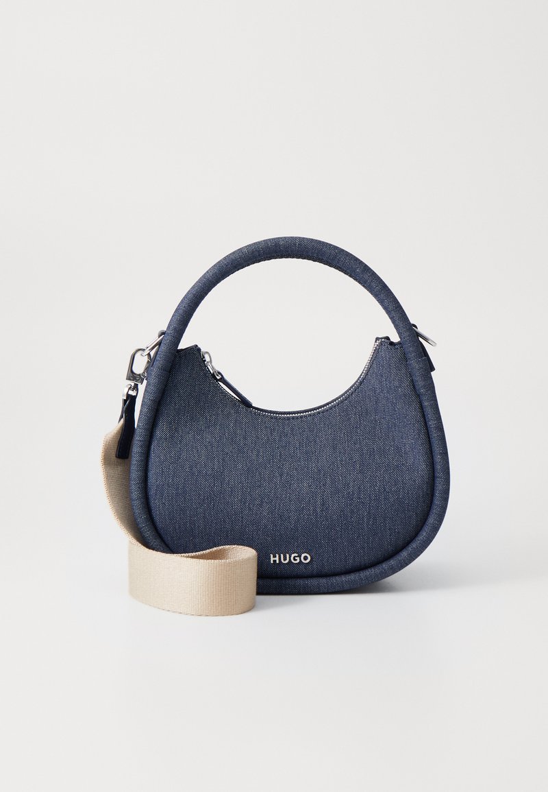 Navy denimitasku, jolla on pyöreä muoto, kontrastivärinen beige olkahihna, hopeinen vetoketju ja HUGO-logo edessä. Pehmeä pinta ja minimalistinen muotoilu.