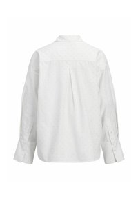 Hvid skjorte med krave, lange ærmer og en front yoke. Har et diskret mønster af små prikker over hele stoffet.