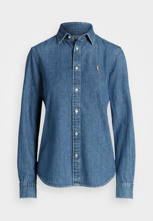 Camicia di jeans blu scuro con bottoni, maniche lunghe, colletto classico e un piccolo logo ricamato sul petto. Dotata di bottoni in metallo.