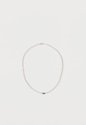 Collana a catena d'argento con piccoli anelli quadrati e una singola pietra preziosa verde rettangolare al centro su sfondo bianco.