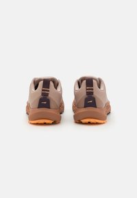 Chaussures de sport marron avec des panneaux texturés gris, des accents de talon violet et des semelles en caoutchouc orange. Possède des languettes robustes à l'arrière pour un enfilage facile.