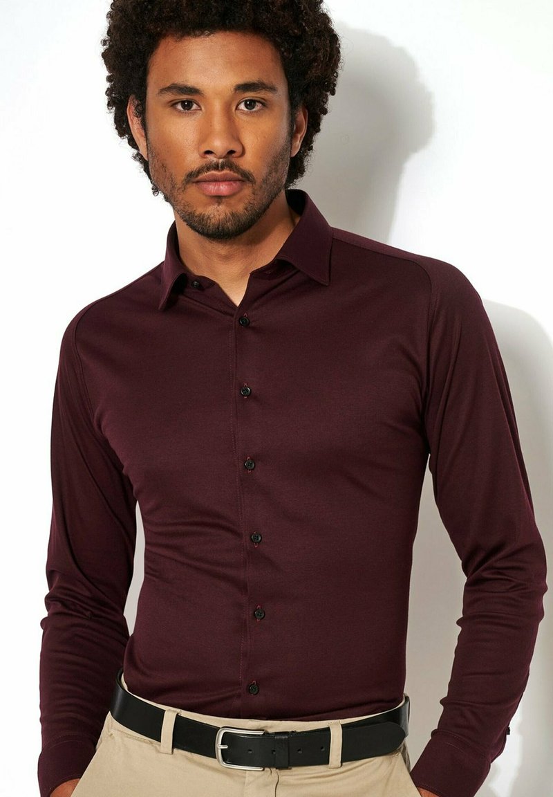 Bordeaux lange mouw shirt, gemaakt van een gladde stof, heeft een knoopsluiting aan de voorkant met zwarte knopen en een klassiek kraagontwerp.