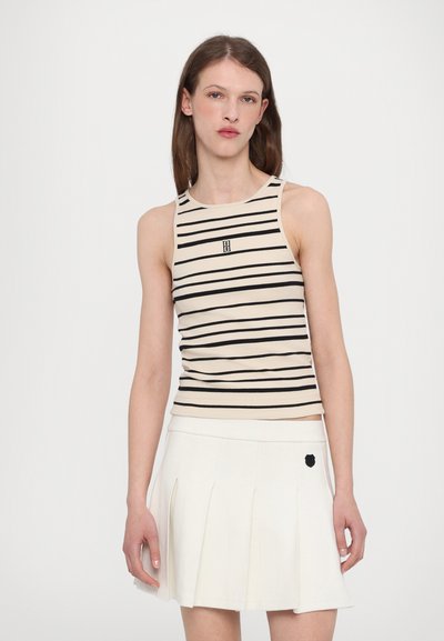 Striped sleeveless top in beige and black, featuring a fitted design with a small embroidered logo. Smooth texture, ribbed fabric.