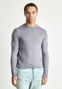 Helehall hall cardigan, millel on ümmargune kaelus, soonikkoes varrukad ja äär. Omab tekstuurset pinda ning väikest logo rinnal. Sobib helesiniste teksadega.