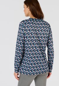 Langsleeve shirt in marineblauw met een geometrisch patroon in lichtblauw, roze en crème. De stof lijkt zacht; ronde halslijn; rechte snit.