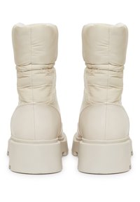 Botas de tobillo acolchadas en beige con punta redondeada, material sintético suave, suela gruesa y detalles de costura sutiles en las costuras.