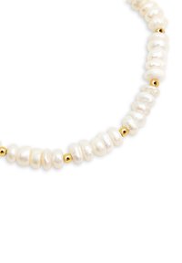 Collana a più fili con irregulari perle bianche e piccole palline dorate, che mette in mostra una superficie liscia e forme organiche.