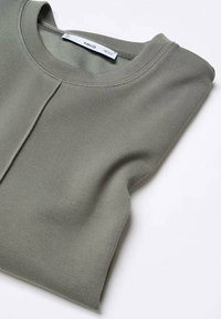 Hellgrauer Pullover, ordentlich gefaltet, aus strukturiertem Stoff mit rundem Ausschnitt und einem dezenten Nahtdetail an der Vorderseite.