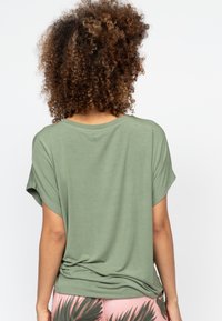 Groene t-shirt met korte mouwen en een relaxte pasvorm, voorzien van een ronde hals. De stof lijkt zacht en lichtgewicht met een subtiele textuur.