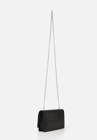 Czarna torebka crossbody z sztucznej skóry z teksturą krokodylej skóry, prostokątna, z srebrnym łańcuszkiem. Otwarta, ukazująca swoje wnętrze.