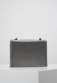 Metaliczna szara torebka o teksturowanej powierzchni, prostokątnym kształcie, zamknięciu na górny zamek błyskawiczny oraz małych, czarnych elementach ozdobnych.