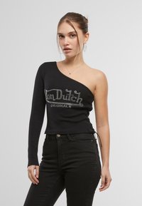 Svart ett-skulder topp laget av stretchstoff, med et rhinestone-logo og snøring på siden. Kombinert med svarte jeans.