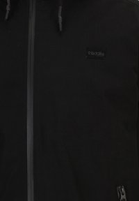 Giacca nera con zip realizzata in un tessuto testurizzato, caratterizzata da una piccola toppa con logo e cordoncini regolabili sulla cappuccio. Dettaglio con tasca zip.