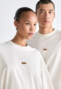 Cremefarvede oversized sweatshirts lavet af bomuld, med et lille brunt "HUGO" logo placeret centralt foran.