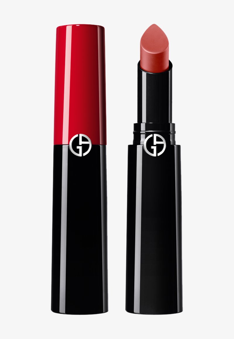 Rouge à lèvres avec un étui noir et rouge et un logo argenté, la couleur du rouge à lèvres est un ton corail atténué et le capuchon est retiré à côté.