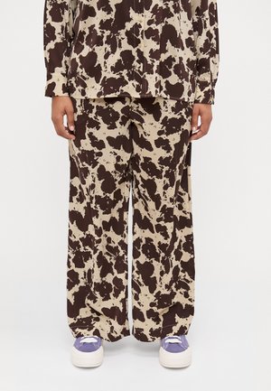 Brown and beige splatter-patterned shirt and wide-leg pants made of a soft material. Paired with purple sneakers and white soles.