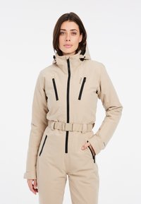 Giacca da sci beige con design aderente, cappuccio regolabile, cerniere nere su tasche frontali e vita con cintura. Tessuto liscio e impermeabile.