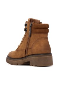 Botín de ante marrón hasta el tobillo con punta redonda, cordones en la parte delantera, cremallera lateral, cuello acolchado y suela de goma gruesa.