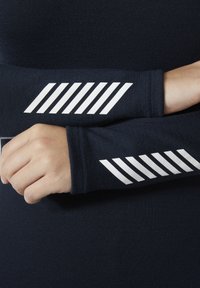 Granatowa koszula z długim rękawem z białymi skośnymi paskami na rękawach. Gładka tekstura i dopasowany krój akcentują kształt ramion.