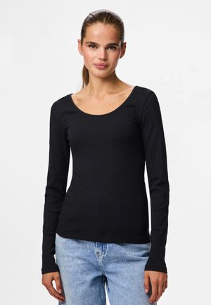Zwarte lange mouwen ribgebreide top met een ronde halslijn, met een aansluitend ontwerp en een zachte textuur, in combinatie met lichtblauwe jeans.