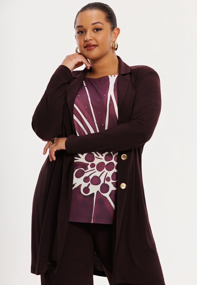 Maroon long cardigan over a patterned purple top with white accents. Features large buttons and soft fabric. Smooth texture, modern design.
