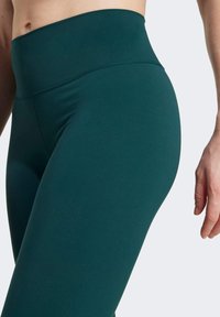 Leggings teal a vita alta con una texture liscia, dotati di una ampia fascia in vita e un design elegante per comfort e flessibilità.