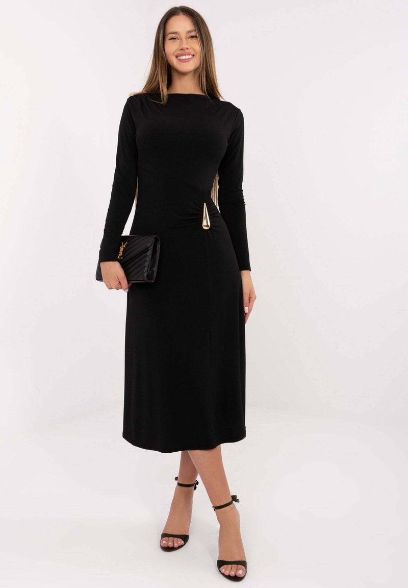 Czarna sukienka z długim rękawem, dopasowanym gorsetem i rozkloszowaną spódnicą, z złotym akcentem w talii. Do kompletu czarna kopertówka.