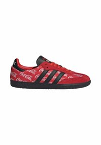Baskets rouges avec des rayures noires et une semelle noire, couvertes de logos blancs « Coca-Cola », avec une languette noire et des lacets rouges.