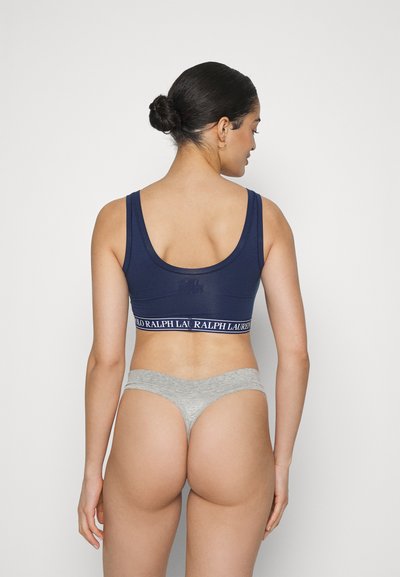 Navy cotton bralette with wide logo band, paired with light gray cotton thong. Simple, form-fitting design with a smooth texture.