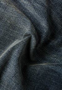 Dark blue denim fabric with a smooth texture and subtle variations in color. The material shows a classic twill weave pattern.