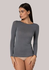 Maglietta grigia a maniche lunghe realizzata in un tessuto leggero, dal design aderente e dalla texture morbida, con scollatura a barca e cuciture minime.