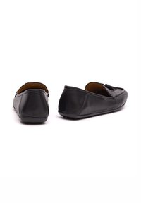 Scarpe slip-on in pelle nera con punta rotonda, cuciture minime, texture liscia e suola in gomma a profilo basso con presa discreta.