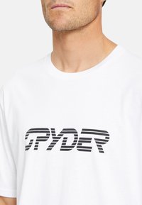 T-shirt bianco in cotone con colletto rotondo, caratterizzato da un logo a strisce nere bold "SPYDER" sopra il petto. Texture liscia, vestibilità casual.