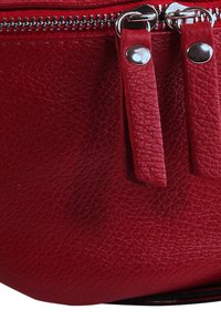 Rode leren handtas met een gestructureerd oppervlak, voorzien van zilverkleurige hardware en een ritssluiting, afgewerkt met twee bijpassende hengsels.