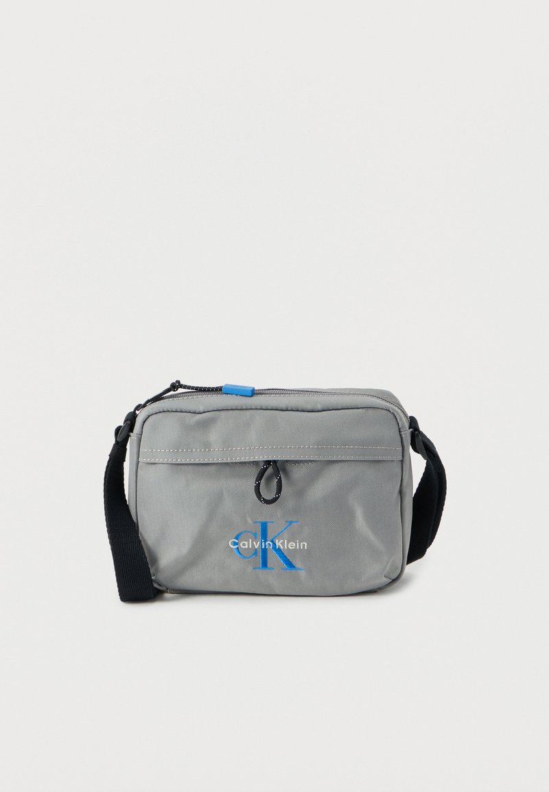 Γκρι τσάντα crossbody από νάιλον με μπλε λογότυπο, κλείσιμο με φερμουάρ και ρυθμιζόμενο μαύρο λουρί. Διαθέτει μικρό βρόχο και ραμμένες λεπτομέρειες.