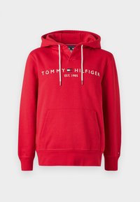 Felpa rossa con cappuccio e cordini bianchi, tasca frontale e testo "Tommy Hilfiger Est. 1985" con logo sul petto.