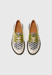 Multicolor shoes with a green fabric upper and a patterned black and white design. Features beige accents, round studs, and beige laces.