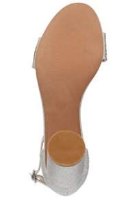 Sandal con tacco metallico argento con tomaia testurizzata, schienale aperto e base del tacco circolare. Suola morbida marrone con superficie rigata per un buon grip.