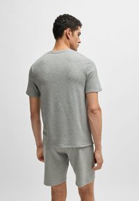 Graues T-Shirt mit kurzen Ärmeln aus strukturierter Baumwolle, runder Ausschnitt und lockerer Passform, kombiniert mit passenden grauen Shorts.